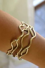 Pulsera rígida de bronce con diseño abstracto de líneas onduladas. Se ajusta a presión.