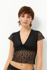 Top de encaje negro con escote en V y tiras de terciopelo. Es de manga corta y corte ajustado.
