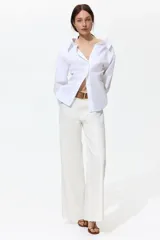 Jean de tiro alto y pierna ancha en denim de algodón blanco, con diseño de cinco bolsillos y bajo sin rematar. Incluye un cinturón de gamuza marrón con hebilla metálica.