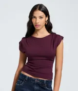 Top ajustado color rojo, con cuello redondo y mangas cortas tipo hombreras o almohadillas. El tejido parece ser de punto o viscosa con buena caída y presenta un fruncido horizontal a la altura de la cintura.