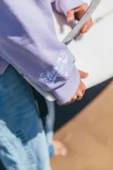 Hoodie de corte oversize color lila, con capucha ajustable mediante cordones, bolsillo frontal tipo canguro y bordado sutil en el pecho.