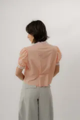 Blusa celeste a rayas blancas, de manga corta abullonada. Cuenta con cuello mao y tapeta de botones con detalles de estampado floreado en tono rosado, presentes también en el cuello y los puños.