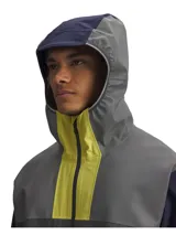Campera impermeable para running con capucha y cierre frontal. Presenta un diseño color block en tonos gris, amarillo neón y azul marino, con bolsillos laterales con cierre y detalles reflectantes.