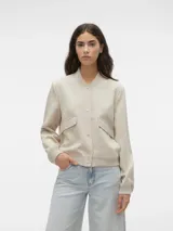 Campera bomber corta de color beige, confeccionada en tejido sarga, con cuello tipo rib, cierre frontal de botones a presión, bolsillos frontales con solapa y puños y dobladillo elasticados.