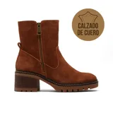 Bota de caña media confeccionada en cuero gamuzado color beige, con cierre lateral metálico, taco cuadrado de madera y suela track dentada.