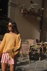 Buzo de punto color beige claro, con tejido acanalado y escote en V. Presenta mangas amplias y corte holgado.