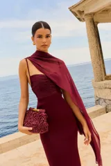 Chal de gasa color burdeos, con diseño drapeado que se extiende desde el hombro.