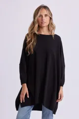 Buzo de punto oversize color negro, con cuello redondo, mangas largas y dobladillo asimétrico más largo en la parte trasera.