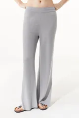 Pantalón gris de tejido de punto confeccionado en lurex. De tiro alto con elástico en la cintura, la pierna se ensancha en el ruedo y cuenta con tajos en los laterales.