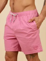 Short de baño tipo volley color rosado, con cintura elástica y cordón ajustable. Presenta bolsillos laterales y un pequeño bordado circular en la pierna izquierda.
