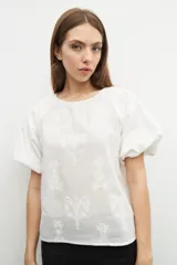 Blusa amarilla con estampado floral, mangas cortas abullonadas y cuello redondo.