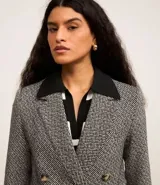 Blazer de tweed gris con diseño de espiga, doble botonadura, solapas de muesca, bolsillos cargo frontales y corte clásico.