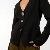 Cárdigan negro de tejido de punto de canalé, con escote en V, cierre frontal con botones dorados y mangas largas.