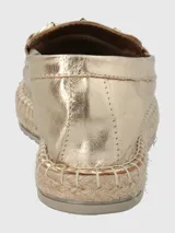 Alpargatas tipo slip-on en cuero metalizado color dorado, con detalle de herraje metálico en el empeine y suela con borde de yute trenzado.