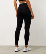 Pantalón deportivo tipo legging de la marca Get Over, confeccionado en microfibra elástica con cintura cruzada y detalle de viés contrastante.