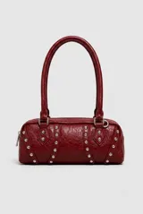 Cartera tipo baguette de cuero sintético en color granate, con diseño cilíndrico, doble asa de hombro y detalles de tachas metálicas plateadas. Cuenta con cierre superior.