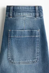 Jean de tiro alto en denim de algodón con leve stretch. Presenta piernas amplias, corte holgado, bolsillos tipo parche en la parte frontal y raya marcada a lo largo de las piernas. Incluye cierre y botón metálico.