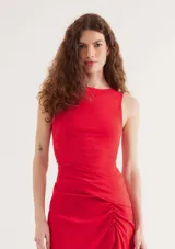 Top rojo sin mangas confeccionado en tejido de punto, con cuello redondo alto y diseño ajustado con detalles de pliegues asimétricos en el lateral.