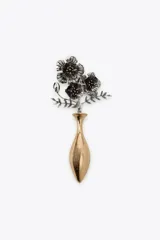 Broche metálico con diseño de un jarrón dorado y un ramo de flores plateadas con centros dorados.