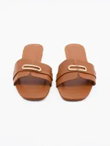 Sandalia marrón de cuero sintético con tira ancha sobre el empeine y detalle de hebilla dorada.