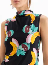 Top negro sin mangas de corte ceñido, con cuello alto y estampado colorido de frutas y labios.