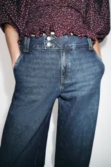 Jeans de tiro bajo con pernera recta y bajo con vuelta. Cuenta con cinco bolsillos y cierre frontal con cremallera y botones.