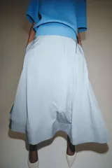 Falda midi de tiro alto en color negro, con diseño en línea evasé y cierre de cremallera oculta en la costura.