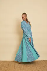 Vestido largo de algodón con estampado de mandalas en tonos celestes y azules, combinado con gajos laterales lisos en color turquesa. Presenta cuello mao con escote en V, mangas largas y silueta amplia y fluida.