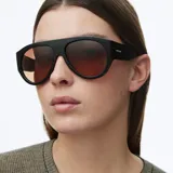 Lentes de sol estilo aviador con montura oversized de color negro y lentes polarizados en tono marrón. Presentan un diseño retro de líneas limpias y estructura robusta.