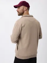 Campera de felpa color beige con cierre frontal completo, cuello alto y puños y ruedo acanalados.