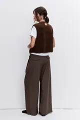 Chaleco de textura tipo corderito en color marrón chocolate, con cuello redondo, cierre frontal con botones y bolsillos laterales.