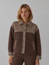 Campera corta de lana con diseño en bloques de color marrón liso y textura tweed en la parte superior, cuello camisero, cierre frontal con botones metálicos y bolsillos ribeteados.