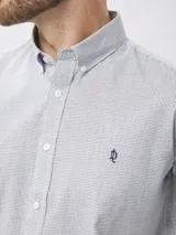 Camisa de manga larga con estampado de microcuadros en tonos azul y blanco. Presenta cuello clásico con botones, cierre frontal abotonado y detalle de logo bordado en el pecho.
