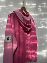 Buzo oversize de plush color rosa chicle, con cuello alto, cierre frontal parcial, capucha y bolsillo tipo canguro. Presenta puños elásticos y cordón ajustable en el ruedo.