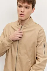 Campera bomber de gabardina color tostado, con cierre frontal y bolsillos laterales, puños y cintura elastizados de rib.