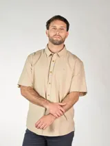 Camisa de lino color beige, de manga corta, con cuello clásico y cierre frontal con botones.