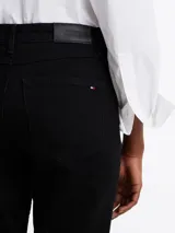 Pantalón de jean negro de corte recto y tiro medio, con cierre de cremallera y botón, cinco bolsillos, y cinturón de cuero negro con hebilla plateada.