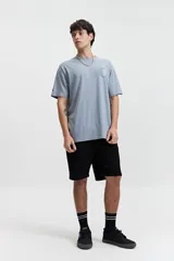 Remera negra de manga corta con cuello redondo y fit regular. Presenta un estampado frontal con gráficos circulares y texto en blanco y naranja.