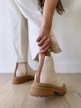 Botas Chelsea de cuero color crudo con elástico lateral, suela track color caramelo y tirador trasero de cuero con textura croco color marrón.