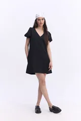 Vestido corto negro con escote en V, mangas cortas abullonadas, silueta suelta y costuras visibles en el frente y la espalda.