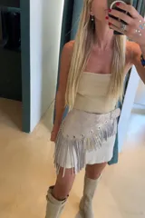 Faja de cuero color beige con flecos, hebilla y apliques metálicos.