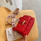 Cartera roja con correa de tela estampada y cierre con hebilla dorada.