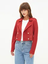 Chaqueta corta tipo blazer en color bordó, con diseño de doble botonadura frontal, solapas clásicas y detalles de charreteras en los hombros con botones metálicos.
