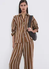 Pantalón tiro medio de corte recto con diseño estampado a rayas, detalle de pinzas, bolsillos laterales y cierre oculto con ganchos y cremallera.