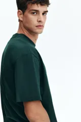 Remera en punto de algodón verde oscuro, con cuello redondo ribeteado, hombros caídos, mangas cortas y bajo recto de corte relajado.