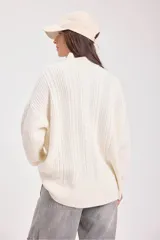 Sweater de punto negro con diseño de trenzas verticales, cuello alto y corte holgado de estilo oversize.