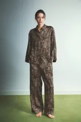Pijama de dos piezas con estampado animal print de leopardo. Incluye una camisa de manga larga con cuello camisero y cierre frontal de botones, y un pantalón de corte recto y holgado con cintura elástica.
