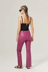 Pantalón de cuero rosa chicle, de corte recto, tiro medio, cierre lateral plateado y tajos en el dobladillo.