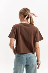 Remera oversize crop marrón de corte amplio y largo corto, con mangas cortas y cuello redondo.