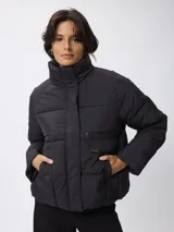 Campera puffer de nylon color negro, con cuello alto, cierre frontal con cremallera y botones a presión. Presenta bolsillos frontales con solapa y diseño acolchado.